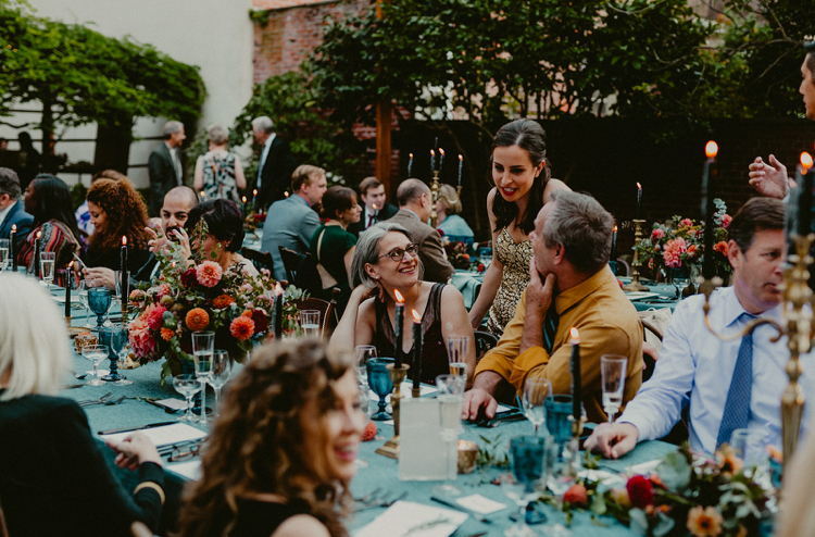 Powel House Wedding Reception | Guests enjoying dinner in the garden surrounded by lush autumn floral centerpieces in peach and red with taper candles and blue linens | Flowers by Love 'n Fresh Flowers | Photo by Chellise Michael Photography