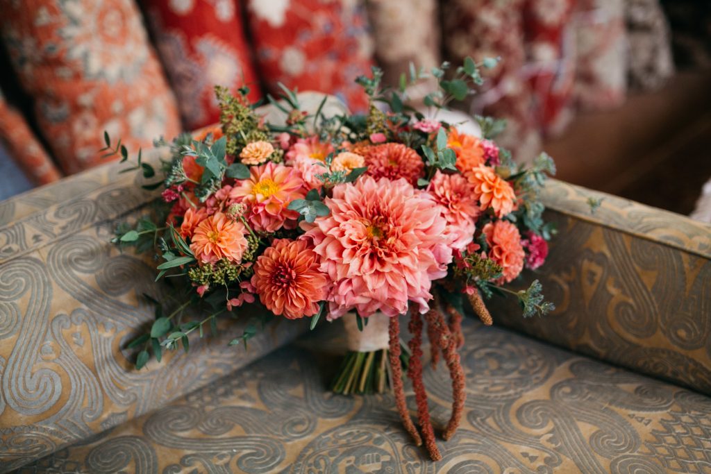 Bridal bouquet featuring colorful dahlias in sunset hues of persimmon, peach, garnet, and orange. | Material Culture Colorful Same-Sex Wedding | Philadelphia | Flowers by Love 'n Fresh Flowers | Photo by Peach Plum Pear Photography