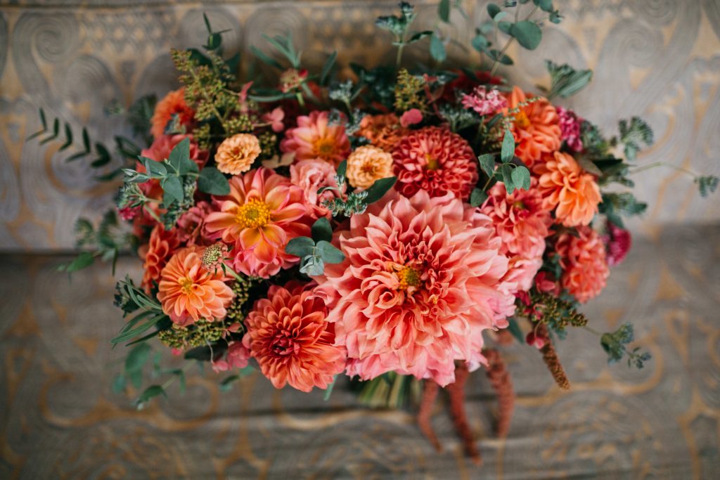 Bridal bouquet with vibrant colors of coral, peach, and orange. | Material Culture Colorful Same-Sex Wedding | Philadelphia | Sustainable Wedding Flowers by Love 'n Fresh Flowers | Photo by Peach Plum Pear Photography