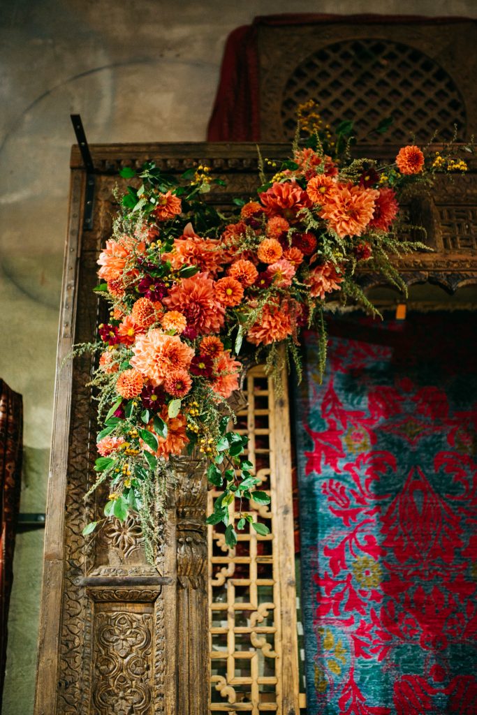 Lush, textural, colorful flowers attached to a doorway for the wedding ceremony. | Material Culture Colorful Same-Sex Wedding | Philadelphia | Sustainable Wedding Flowers by Love 'n Fresh Flowers | Photo by Peach Plum Pear Photography
