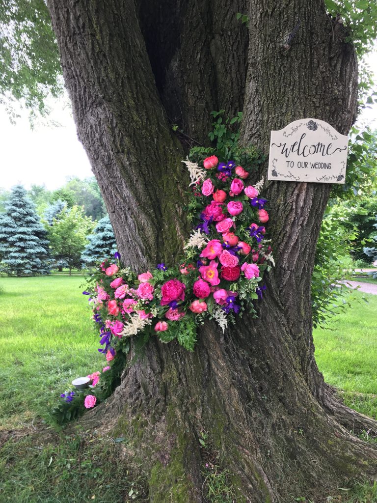 Floral Installations up a tree trunk for a garden wedding are a whimsical and dramatic statement || Floral design by Love 'n Fresh Flowers in Philadelphia